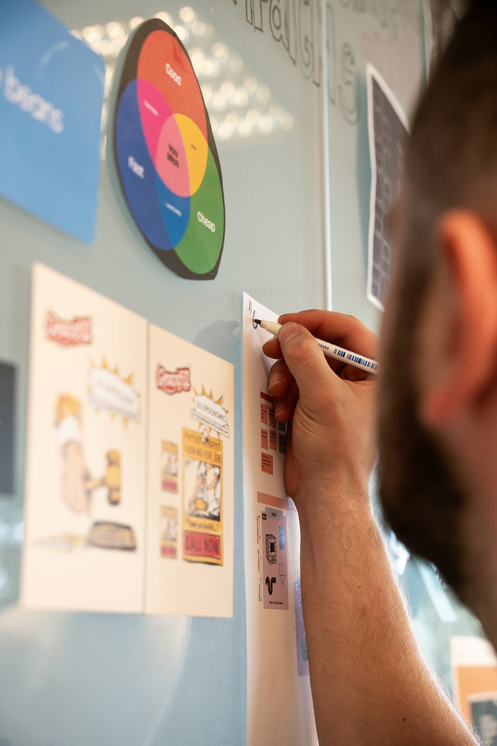 Designer pinning advertising sketches to a wall