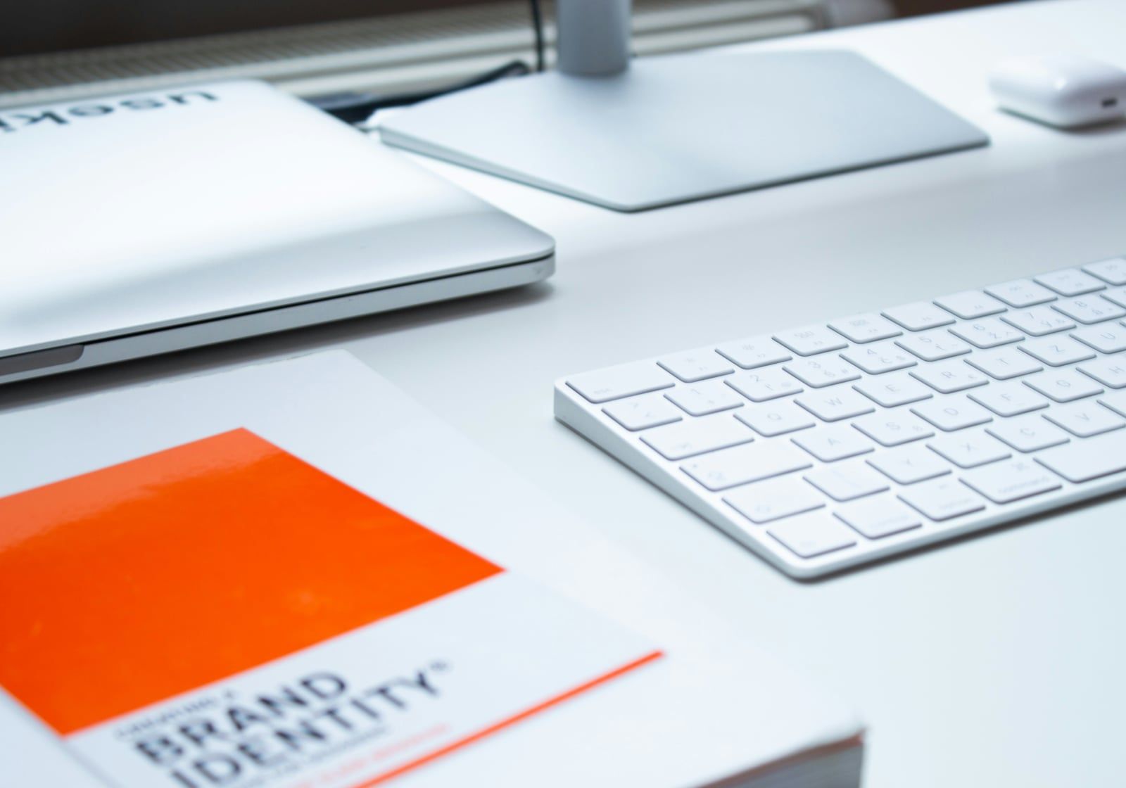 Brand identity book on a desk beside a keyboard and laptop